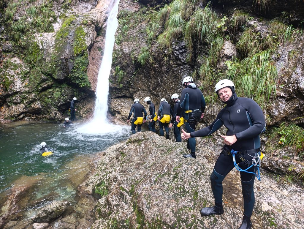 Group canyoning adventure near Bovec in the Soča Valley, Slovenia with participants standing next to a waterfall during a guided tour.